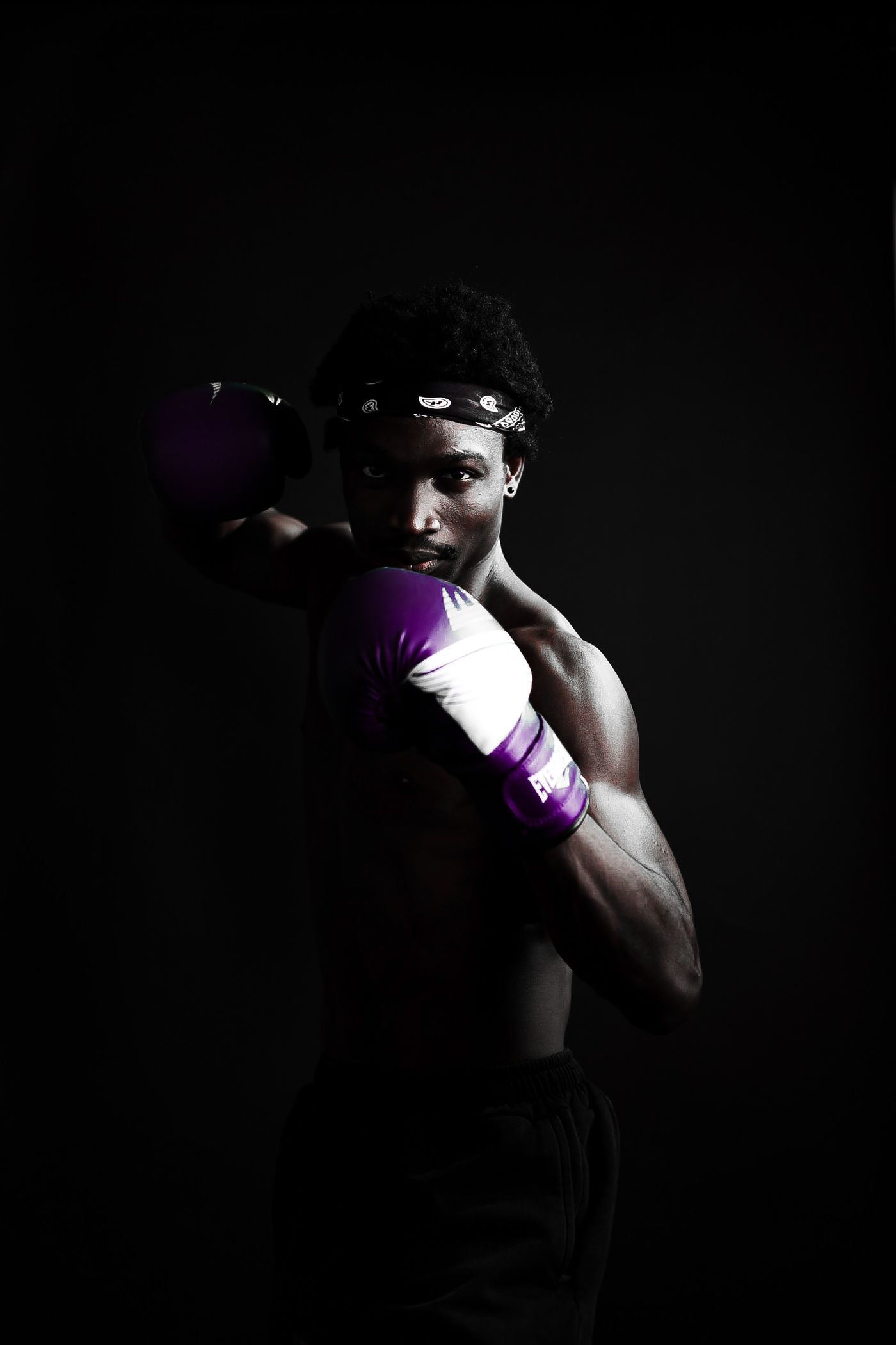 A boxer holding guard, rim-lit against the dark of the gym